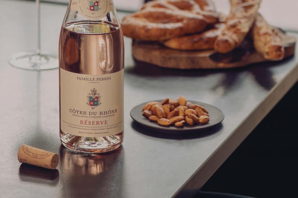 Famille Perrin's Cotes du Rhone Rosé sitting on a counter next to food.