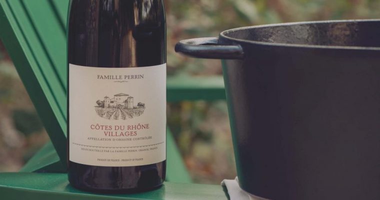 A bottle of Cotes du Rhone Villages next to a pot with food.