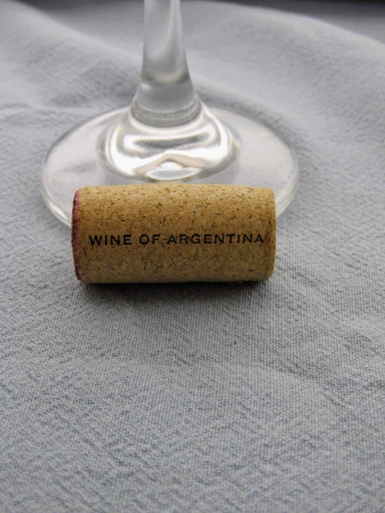 Cork that says Wine of Argentina sitting in front of a glass.