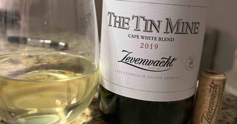 A bottle of Zevenwacht "Tin Mine" white blend with a half-full stemless wine next to the bottle.